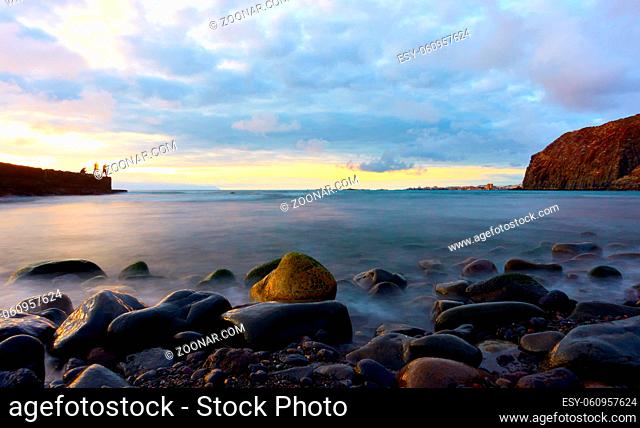 The Atlantic ocean and stones on the beach at sunset in Tenerife island, The Canaries - Long exposition