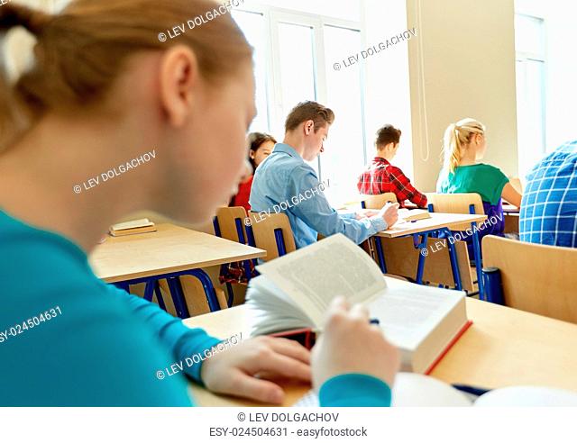 education, learning and people concept - group of students with books writing school test