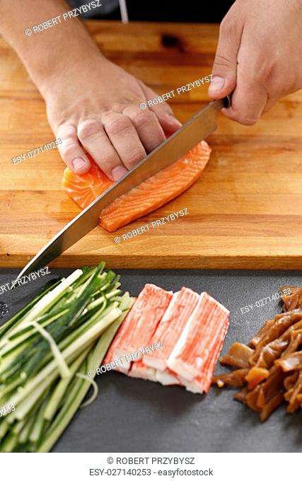 Sushi , etapy przygotowywania sushi z lososiem, paluszkiem krabowym, ogórkiem tykwa zawinietego w glon nori