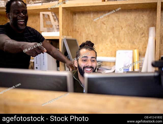 Laughing businessmen working at computers in office