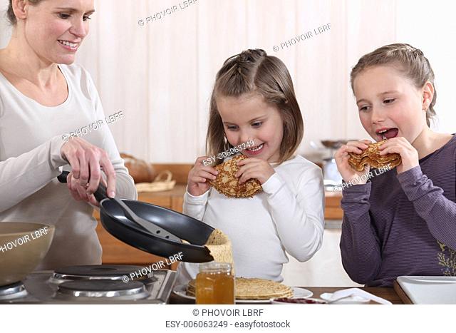 A mother making crepes for her daughters