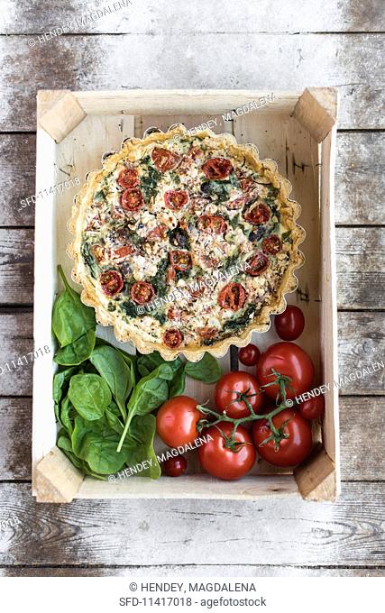 Tomato tart with spinach and feta cheese in a crate (seen from above)