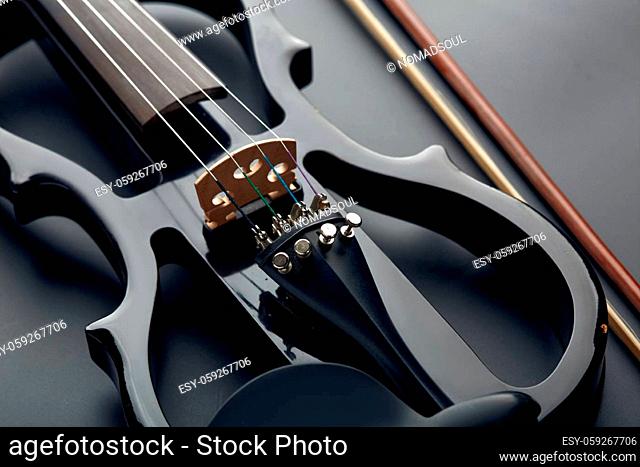 Modern electric violin and bow, closeup view, nobody. Classical string musical instrument, black background, electro viola