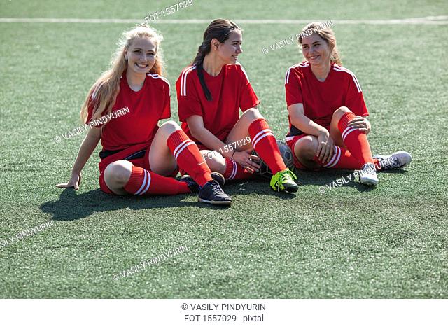 Cheerful soccer players talking while resting on field
