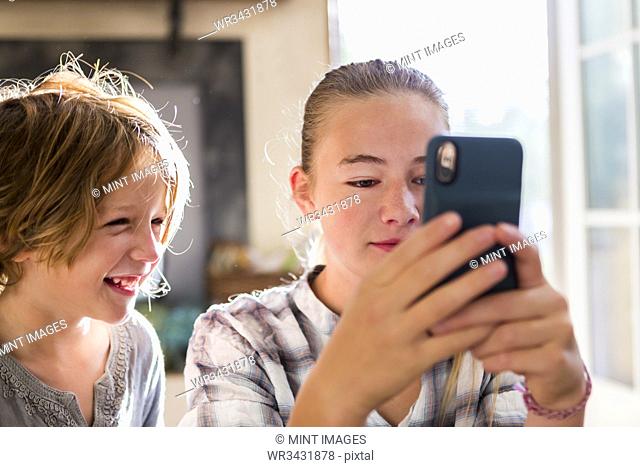 A brother and sister holding up a smart phone