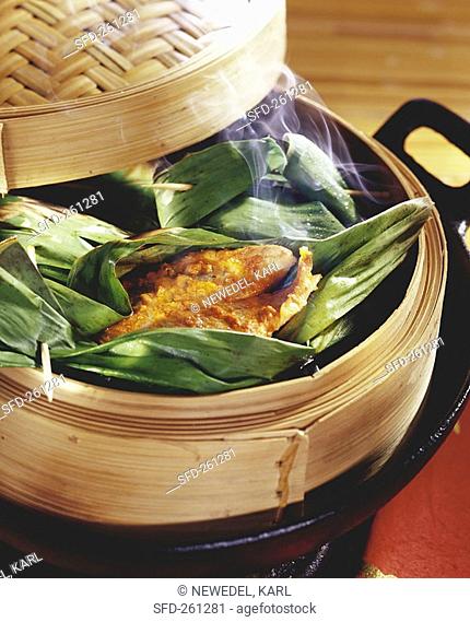 Trout in banana leaf in bamboo steamer