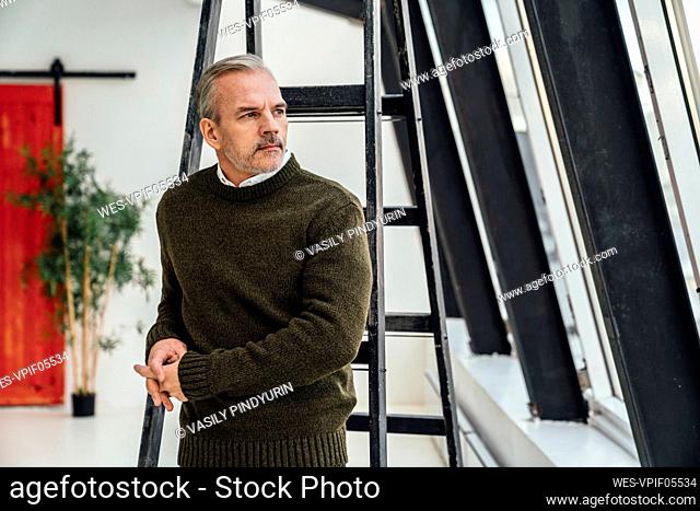 Thoughtful businessman with hands clasped in office