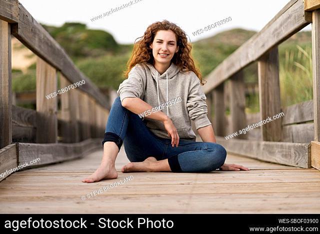 Young woman sitting on wooden bridge during vacations