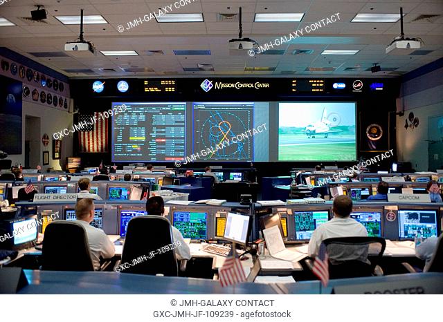 Flight controllers watch the big screens from their consoles in this overall view of the space shuttle flight control room in the Mission Control Center at...