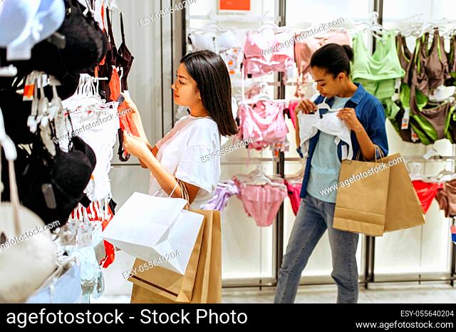 Two girls choosing lingerie in clothing store. Women shopping in fashion boutique, shopaholics, shoppers looking underwear in shop