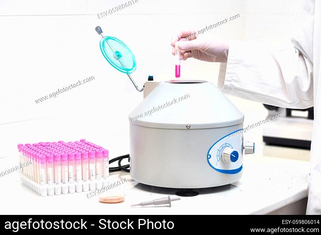 Technician loading a sample to centrifuge machine in the medical or scientific laboratory