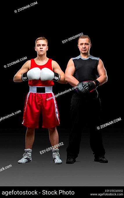 Young teen boxer in blue suit and black gloves working out with boxing coach holding paw. Isolated on white. Copy space