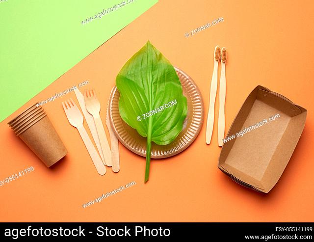 disposable paper utensils from brown craft paper and recycled materials on a orange green background, plastic rejection concept, zero waste