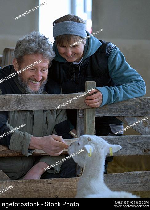 15 March 2021, Brandenburg, Roskow: Farmer Katja Behling and her husband Christoph (a trained shepherd) stroke a shorn ewe of the Skudden breed in the barn on...