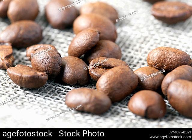 roasted coffee beans on coarse linen material during sale in the store, photo closeup