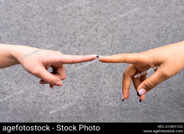 Hands of two young women touching with index fingers