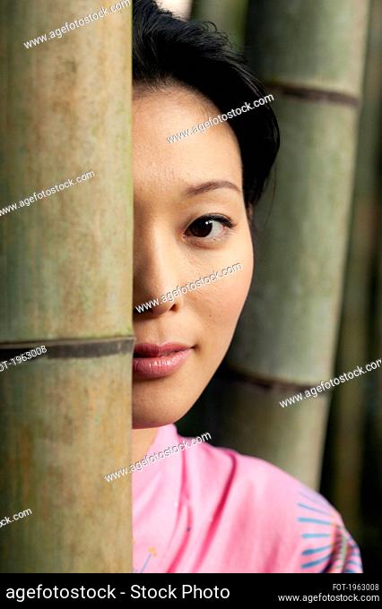 Close up portrait beautiful young Asian woman behind bamboo
