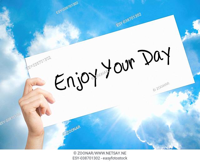 Enjoy Your Day Sign on white paper. Man Hand Holding Paper with text. Isolated on sky background
