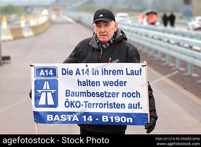 14 December 2023, Saxony-Anhalt, Lüderitz: Herbert Leue, stands with a protest poster for the continued construction of the A14 on the newly opened...