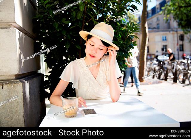 Woman wearing straw hat using smart phone at table