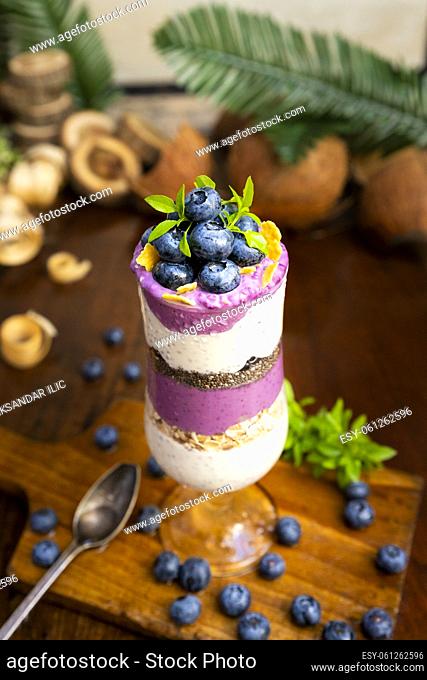 Blueberry smoothies with chia seeds in glass with fresh berries and mint on rustic wooden table
