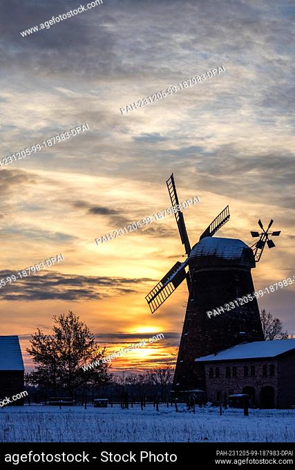05 December 2023, Brandenburg, Leuthen: The sun rises behind the historic mill in the Dörrwalde district of Großräschen. Built in 1845