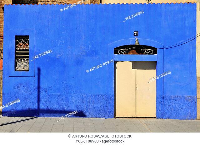 Door in a blue wall in the port district of Tarragona, Catalonia. Spain