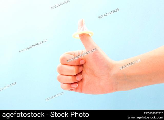 Condom on thumb up gesture. Female hand with thums up and condom on thumb. Safe sex concept