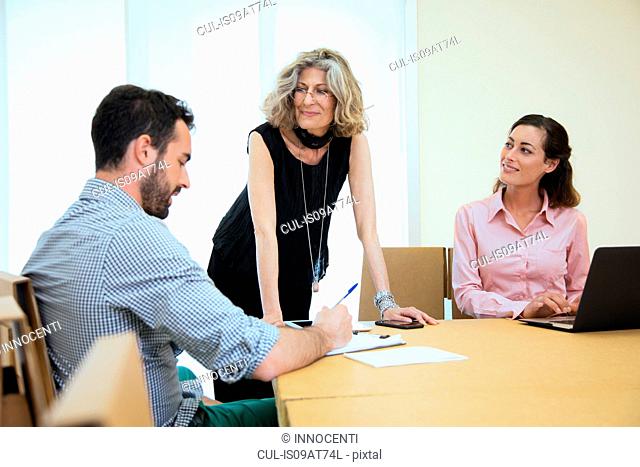 Three designers brainstorming at boardroom table