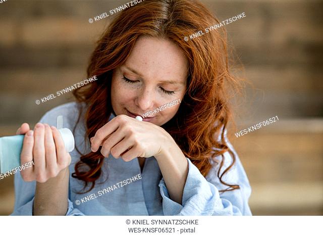 Portrait of redheaded woman smelling cream