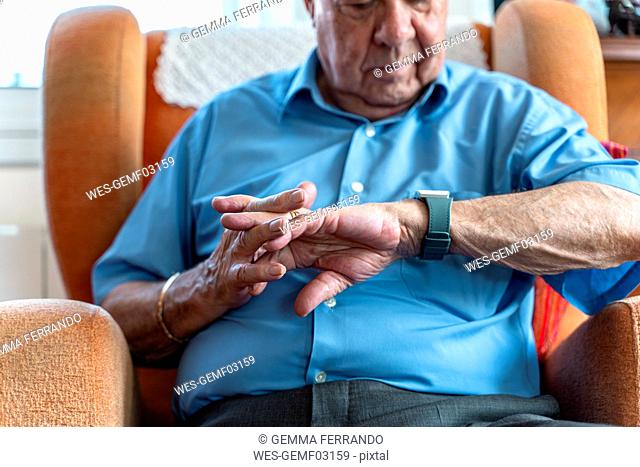 Elderly man wearing a smart emergency alarm bracelet around wrist at home