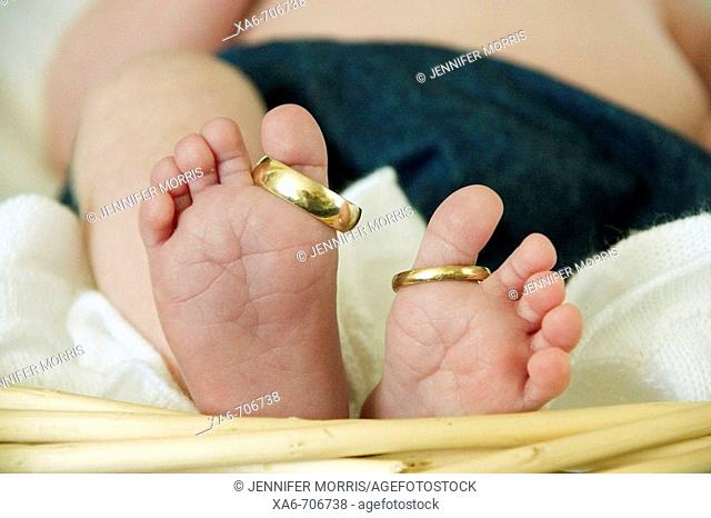 A newborn baby's feet with her parents' wedding rings on her toes