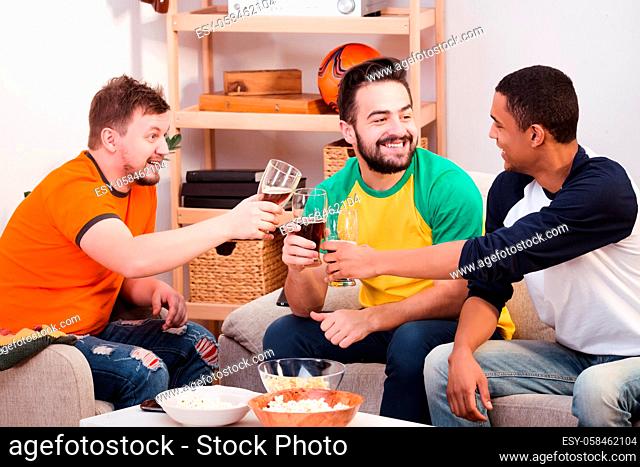 Happy friends drinking beer at home. Hnadsome men communicating and spending their weekends all together