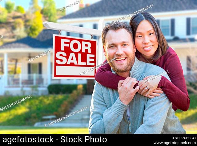 Mixed Race Caucasian and Chinese Couple In Front of For Sale Real Estate Sign and House