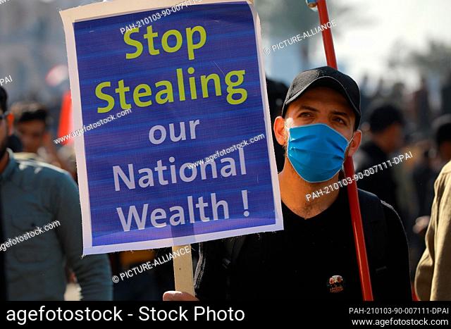 03 January 2021, Iraq, Baghdad: An Iraqi man holds a placard during a protest at Tahrir Square to commemorate the one-year anniversary of the assassination of...