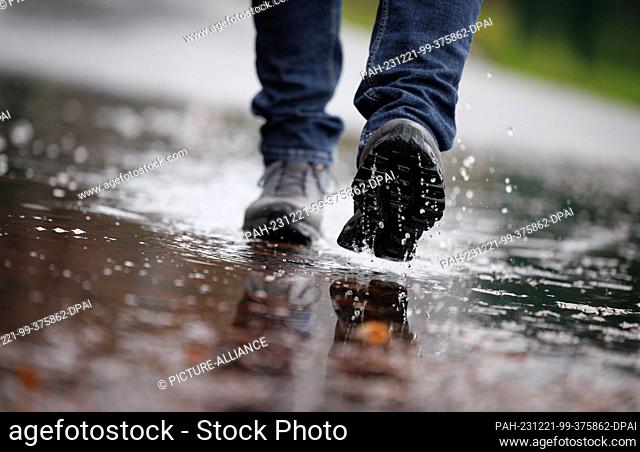 21 December 2023, Lower Saxony, Osnabrück: A walker crosses the part of a footpath that has been flooded by the rain. The German Weather Service is expecting...
