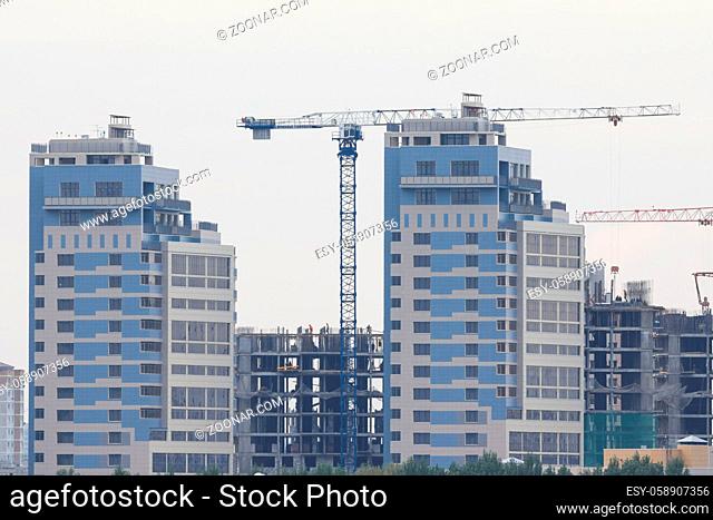 Construction site - modern living building - cranes and workers, telephoto shot