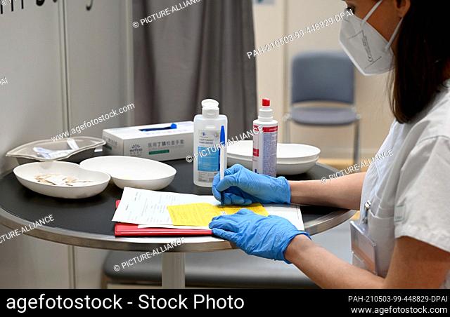 03 May 2021, Baden-Wuerttemberg, Stuttgart: A doctor fills out a vaccination certificate after a Corona vaccination in the vaccination centre of the Stuttgart...
