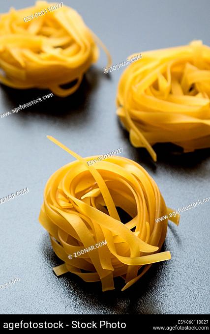 raw dry tagliatelle pasta on black table