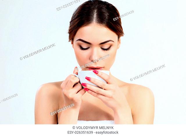 The attractive brunette beautiful girl with cup of herbal tea on white background, youth and skin care concept