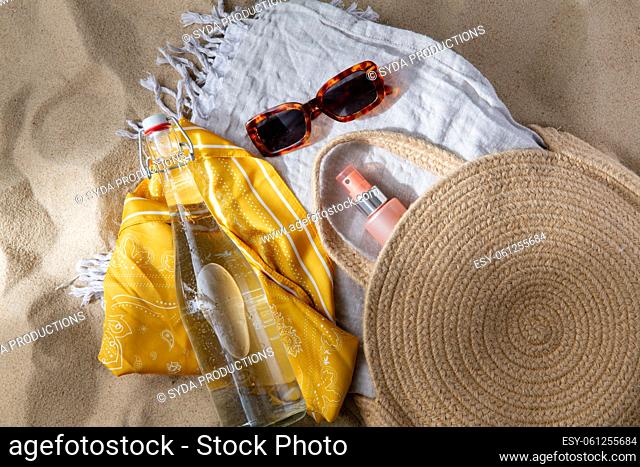 sunglasses, bag, water bottle, sunscreen on beach
