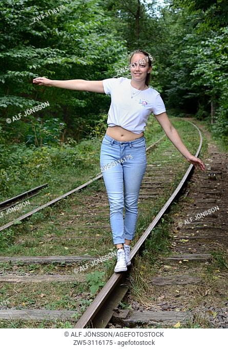 Young woman, 25 years old, balancing on a railroad track in Fyledalen, Scania, Sweden; Europe