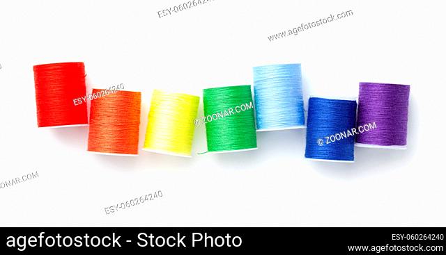 Sewing threads arranged like rainbow colors isolated on white background. Top view