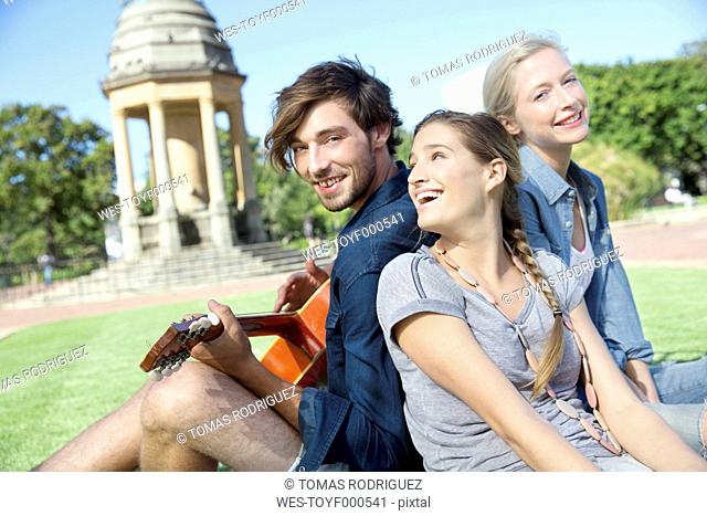 Happy friends with guitar in park