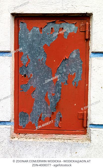 Eine rote Tür aus Metall mit abgeblätterter roter Farbe