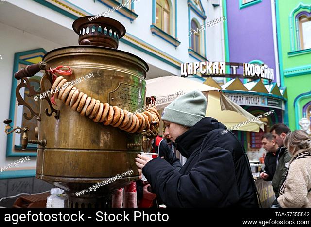 RUSSIA, MOSCOW - FEBRUARY 25, 2023: A woman pours tea from a samovar, a traditional Russian teapot, during a celebration of Maslenitsa [Pancake Week] at the...