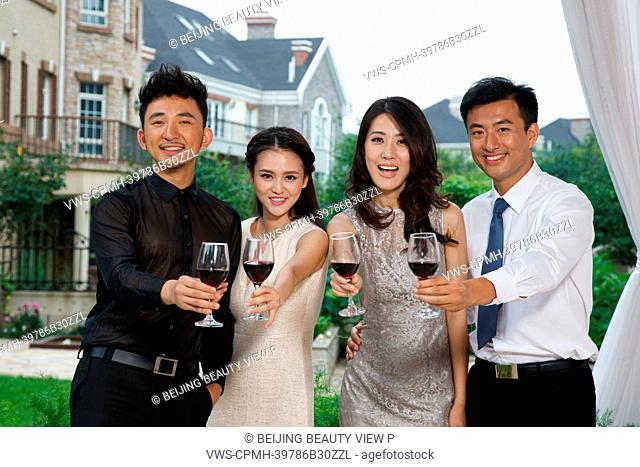 Young people holding glasses of red wine outside