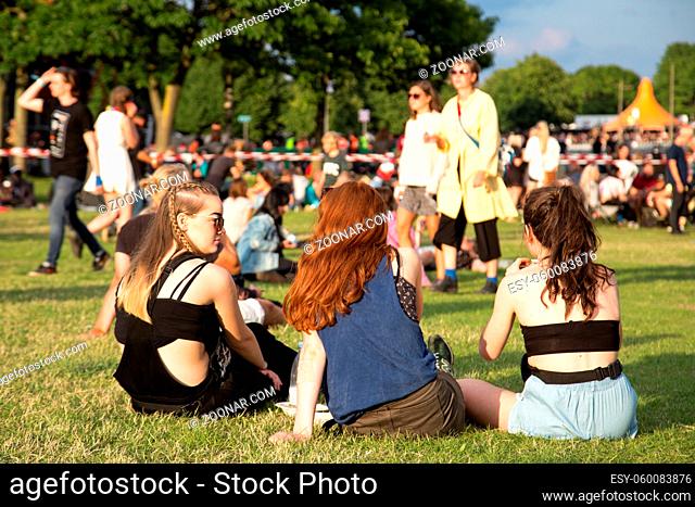 Roskilde, Denmark - June 29, 2016: People sitting on grass and enjoying sunshine and concerts at Roskilde Festival