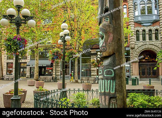 A totem pole with the Pioneer Building in the background on Pioneer Square in Seattle in Washington State, USA