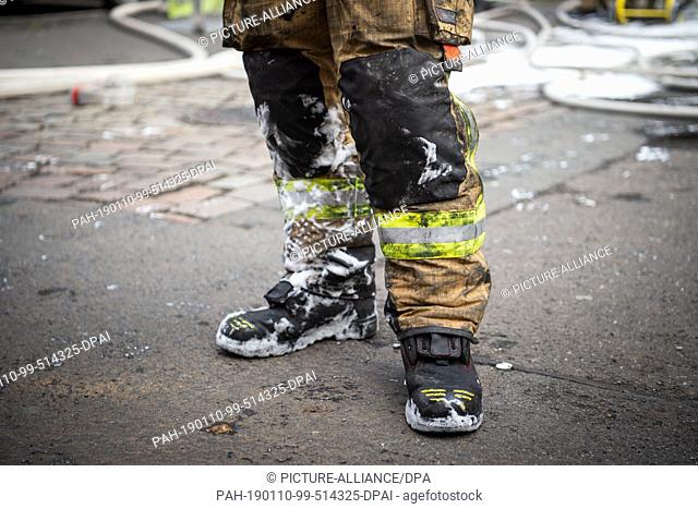 10 January 2019, Berlin: A firefighter is standing in front of an underground car park with foam and soot of dirty clothes after a fire